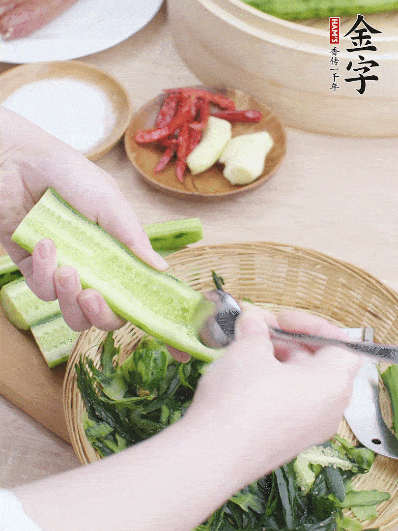 黃瓜削皮，對半切開，勺子挖去內(nèi)瓤，斜刀切片。青蒜斜刀切段。