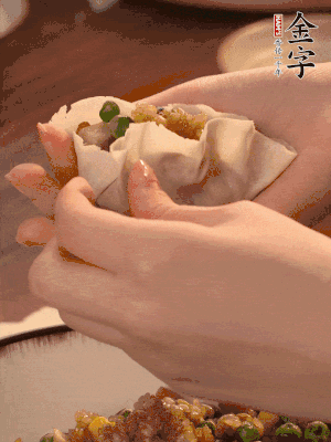 取一大勺餡料放進(jìn)餃子皮里，用大拇指按住頂部餡料，再用虎口掐出形狀。